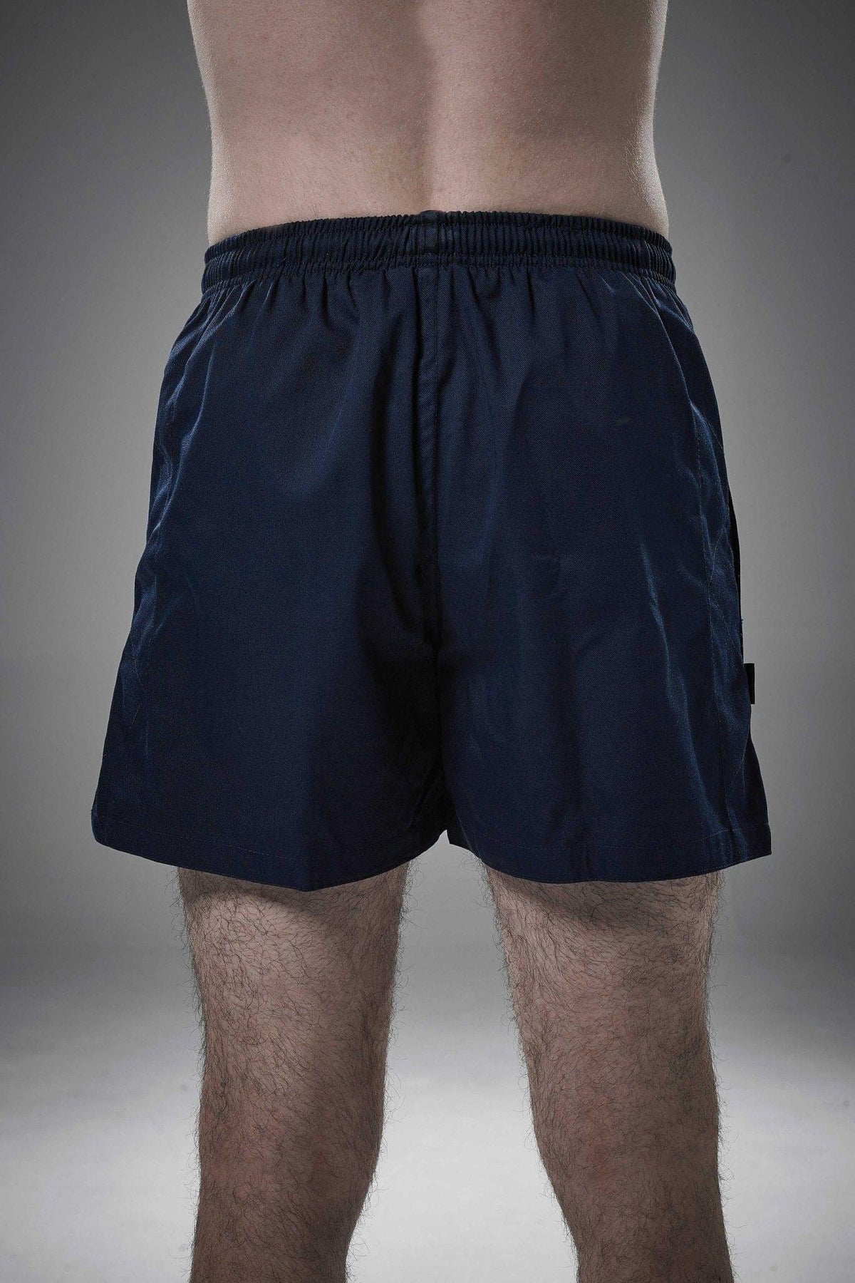 Man wearing navy Optimum Auckland rugby shorts, back view on grey studio background - Optimum